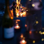 Wine and candles beside a fire pit creating a cozy winter evening atmosphere