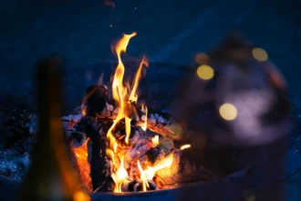 Wine and candles beside a fire pit creating a cozy winter evening atmosphere