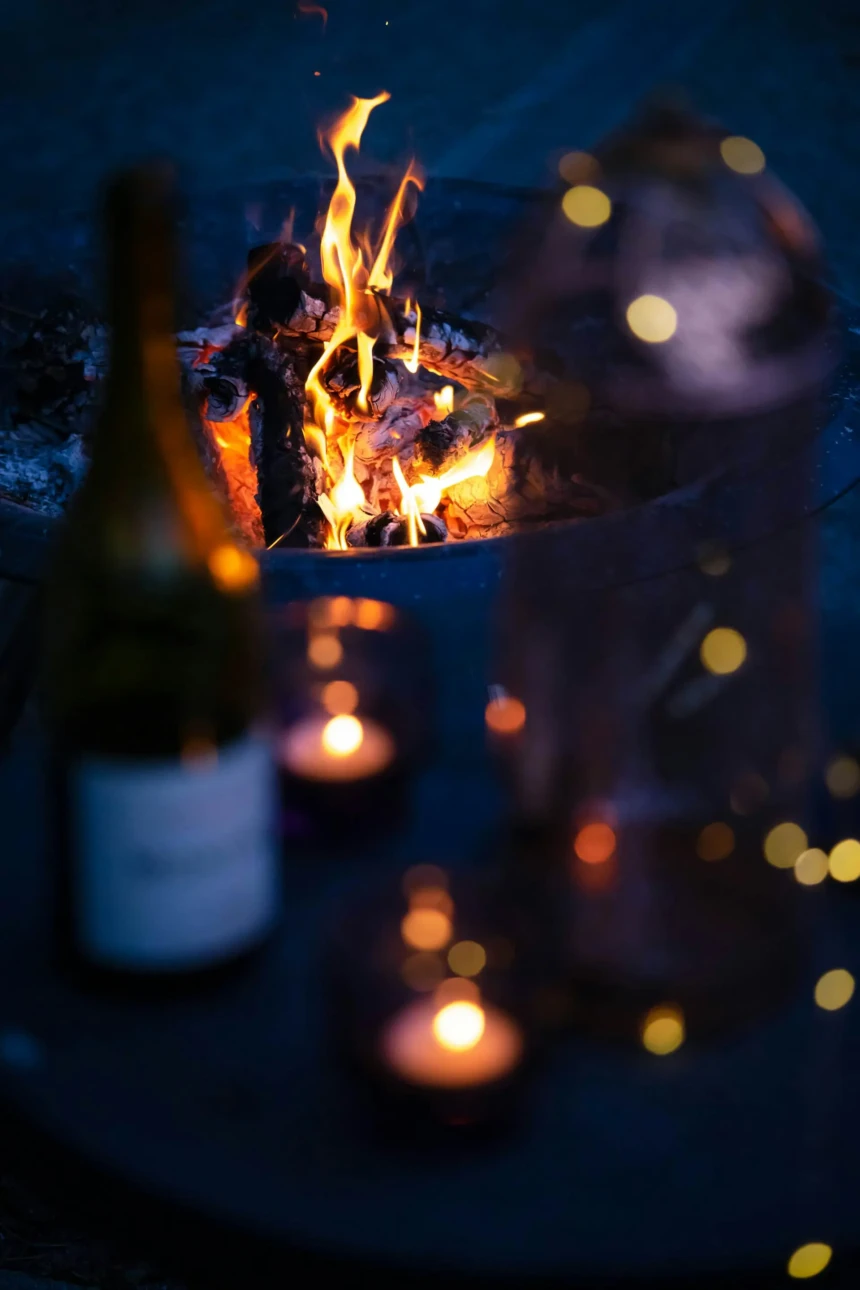 Wine and candles beside a fire pit creating a cozy winter evening atmosphere