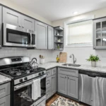 Kitchen with gray painted cabinets and glass doors in a Browns Mills home