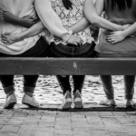 Women standing together with arms linked in solidarity overlooking water