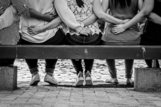 Women standing together with arms linked in solidarity overlooking water