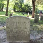 Historic gravestone surrounded by American flags and trees at Timbuctoo Cemetery in Westampton, New Jersey.