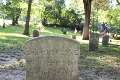 Historic gravestone surrounded by American flags and trees at Timbuctoo Cemetery in Westampton, New Jersey.