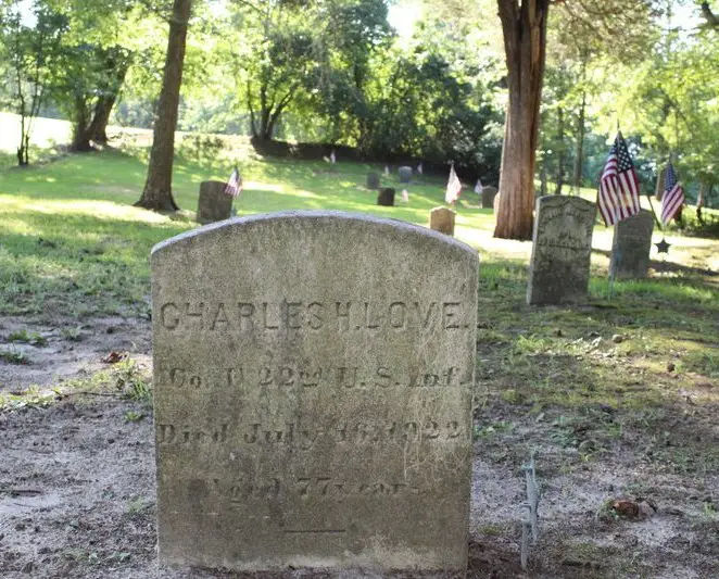 Historic gravestone surrounded by American flags and trees at Timbuctoo Cemetery in Westampton, New Jersey.